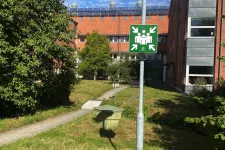 An assembly point sign on a lawn. Photo.