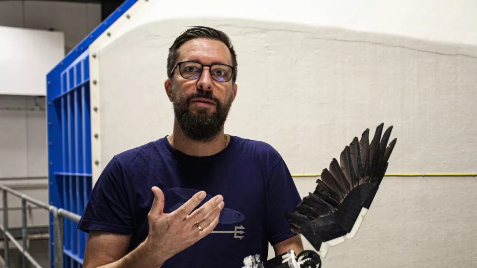 A man holding a feathered robotic wing. Photo.