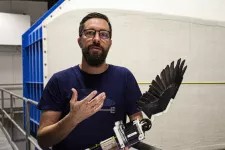 A man holding a feathered robotic wing. Photo.